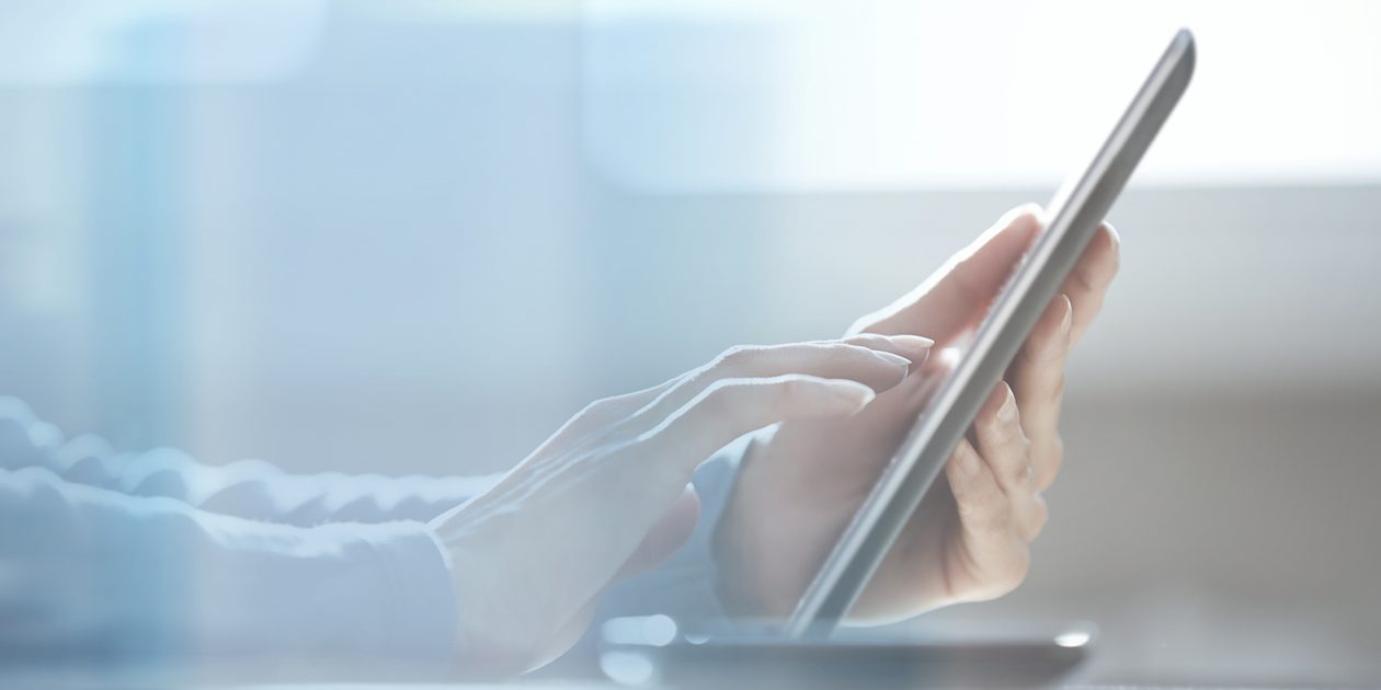 Human hands using tablet computer at office behind the glass door