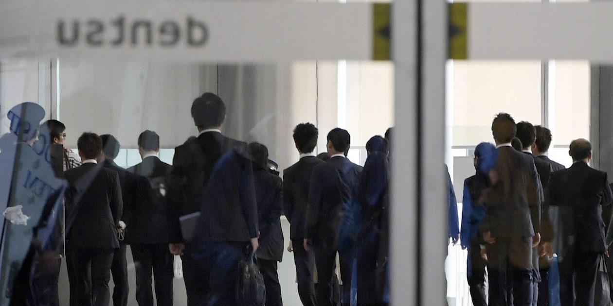 Investigators from the Health, Labor and Welfare Ministry enter the headquarters of Japan's top advertising agency Dentsu in Tokyo Monday.